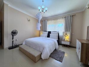 a bedroom with a large white bed and a chandelier at The Terrace Villa in Kampala