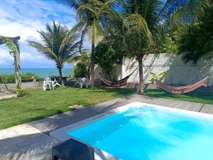 a swimming pool with hammocks and the ocean at Kitnet Terreo Privada 1 in Conde