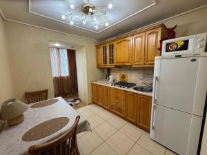 a kitchen with wooden cabinets and a white refrigerator at One bedroom king size center in Dnipro