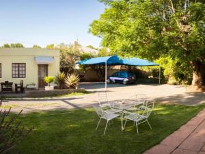 a table and chairs in a yard with a blue umbrella at Oude Pastorie in Cradock