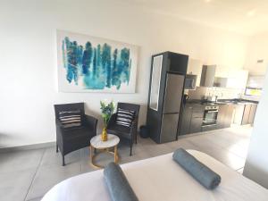 a kitchen with a refrigerator and a table and chairs at Aloe Shore- Whale Watch from Balcony- Stunning in Umdloti