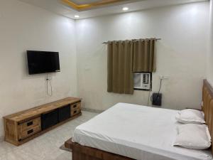 a bedroom with a bed and a flat screen tv at Hotel Elite in Palwal