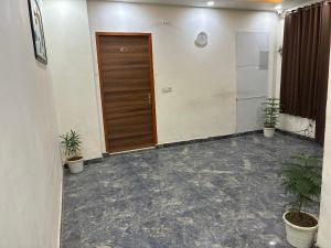 a hallway with a door and potted plants at Hotel Elite in Palwal
