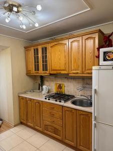 a kitchen with wooden cabinets and a sink and a refrigerator at One bedroom king size center in Dnipro +3 photos