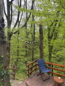 a blue chair sitting on a wooden deck in the woods at Šumarak Weekend House in Arandelovac