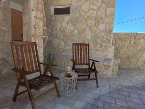 two chairs on a patio with a stone wall at Adria Stone House in Grižane