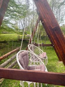a swing with two chairs in a field at Šumarak Weekend House in Arandelovac +1 photo