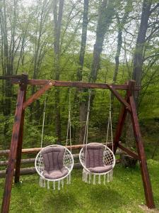 two chairs on a swing in the woods at Šumarak Weekend House in Arandelovac