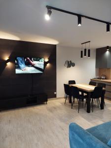 a living room with a table and a tv on a wall at Domki Alpati in Jastrzębia Góra