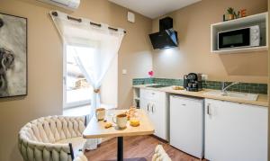 a kitchen with a table and two chairs and a sink at Ecrin de bulles - Jacuzzi & clim in Les Cabannes +4 photos
