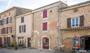 an old brick building with red doors and windows at Ecrin de bulles - Jacuzzi & clim in Les Cabannes