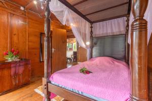 a bedroom with a canopy bed with a pink blanket at écrin de Monpierre in Brion
