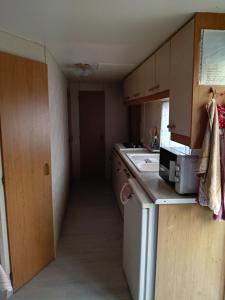 a small kitchen with a sink and a microwave at mobilhome Catalan in Néfiach