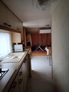 a kitchen with a sink and a room with a bed at mobilhome Catalan in Néfiach