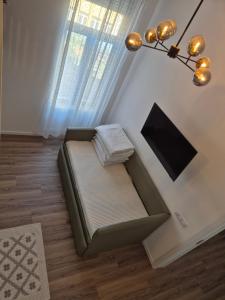 a couch sitting in a living room with a window at Zion Central Apartment in Satu Mare +2 photos