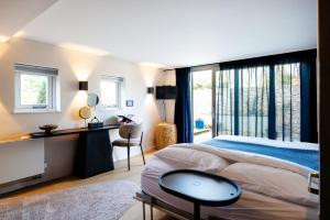 a bedroom with a large bed with a desk and a window at La petite chambre in Bennekom