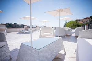 a patio with white chairs and tables and umbrellas at Guesthouse with Suites on the Amalfi Coast - Residence Villa Ruocco near Amalfi - 300sqm Open Terrace near Ravello - Breathtaking View in Scala