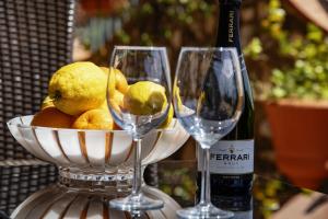 two wine glasses and a bowl of fruit and a bottle at Essence One by Sweet Capri in Capri