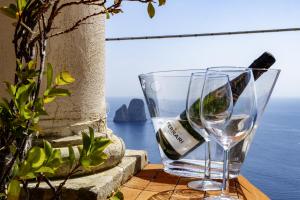 a glass of wine sitting on a table near the ocean at Essence One by Sweet Capri in Capri