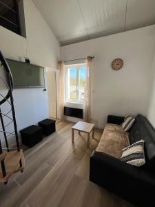 a living room with a black couch and a window at Chez Raphaël et Hiba in Nesles
