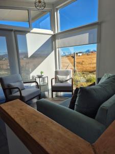 a living room with a couch and chairs and large windows at CABAÑAS PAMPAS AUSTRALES in Puerto Natales