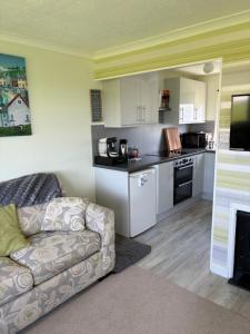 a living room with a couch and a kitchen at Sally Chalet in Hemsby