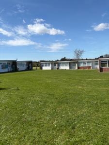 a large grass field with buildings in the background at Sally Chalet in Hemsby