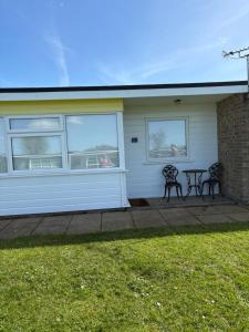 two benches in front of a house with windows at Sally Chalet in Hemsby