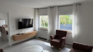 a living room with a tv and a chair and two windows at WorkHome A2 zu 6 in Lünen