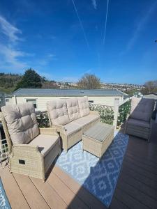 a patio with two chairs and a couch on a deck at Luxury 3 bedroom caravan hobourne Devon bay with hot tub in Goodrington +6 photos