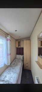 a small bedroom with a bed and a window at Luxury 3 bedroom caravan hobourne Devon bay with hot tub in Goodrington