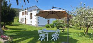 a table and chairs under an umbrella in a yard at Casa Conchas in Ferreira