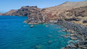 a boat in the water next to a rocky shore at O Marinheiro 15B in Machico