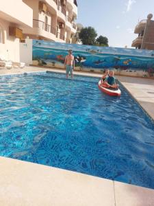 a man and two children in a swimming pool at in luxor apartment in Luxor