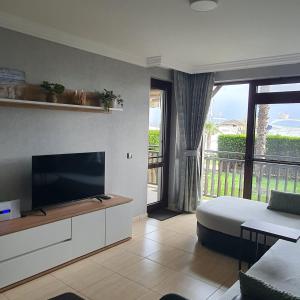 a living room with a television and a large window at Beachfront Apartment with Garden at Venid Sandy Beach - Apartment Marina Dinevi View in Sveti Vlas
