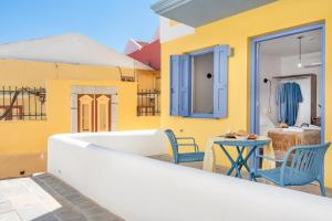 a yellow house with a balcony with a table and chairs at Twelve 12 Islands in Symi +75 photos