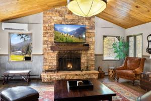 a living room with a stone fireplace with a tv at Secluded River View Hideaway in Hungry Horse