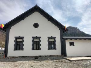 a white building with black windows and a mountain at Piscina Margaia in Lupşa
