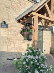 a basket of flowers hanging from the side of a building at Misty View - 2 Bed Cottage in Winchcombe in Winchcombe