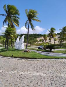 two statues of people in white on the grass with palm trees at Hotel Pirâmides natal in Natal
