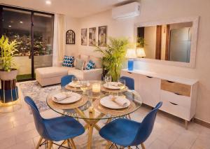 a living room with a glass table and blue chairs at Apartamento con vistas, balcón, gym y parking in Tegucigalpa