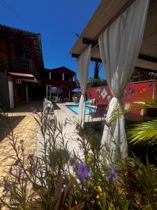 a patio with white curtains and a swimming pool at Pousada N'ativaMar in Guaratuba