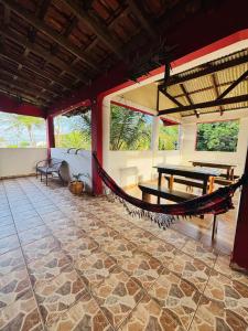a hammock in a room with a table and benches at Pousada N'ativaMar in Guaratuba