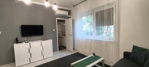 a living room with a tv and a couch and a window at Mérey Apartment in Szeged