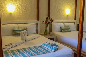 a room with two beds and a vase with flowers at Chez Waffle Hotel in Puerto Aventuras +46 photos
