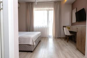 a bedroom with a bed and a desk and a window at ZARO Apartments in Bitola