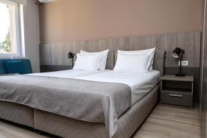 a bedroom with a large bed with white sheets and pillows at ZARO Apartments in Bitola