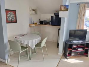 a small kitchen with a table and chairs and a television at Wisteria House in Blean