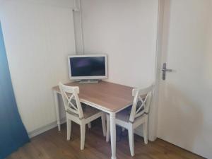 a wooden table with a computer monitor and two chairs at Auberge des Fées in Buttes +2 photos