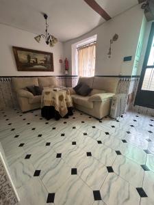 a living room with a couch and a table on a tiled floor at Casa Rincón in Iznatoraf